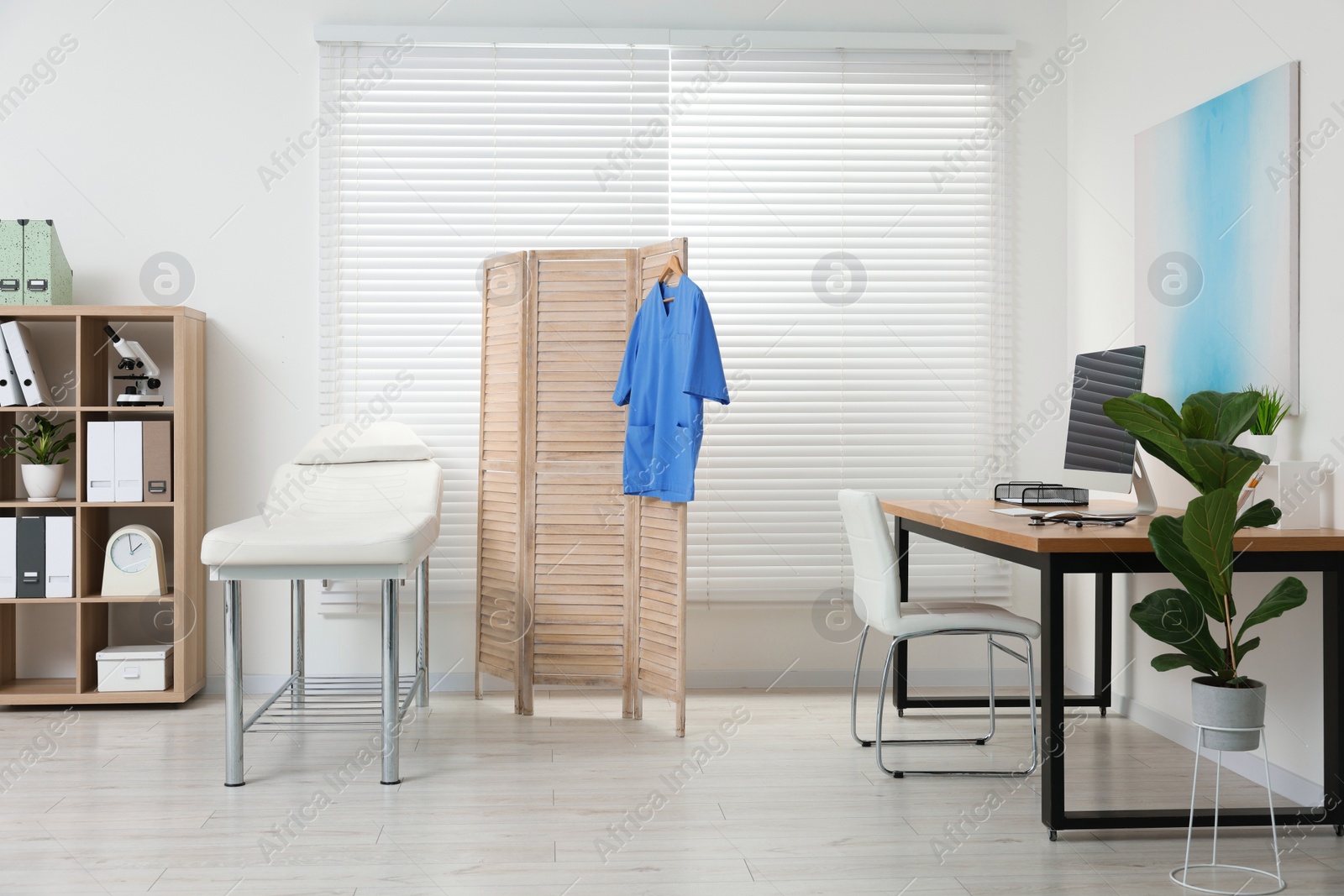 Photo of Modern medical office with doctor's workplace and examination table in clinic