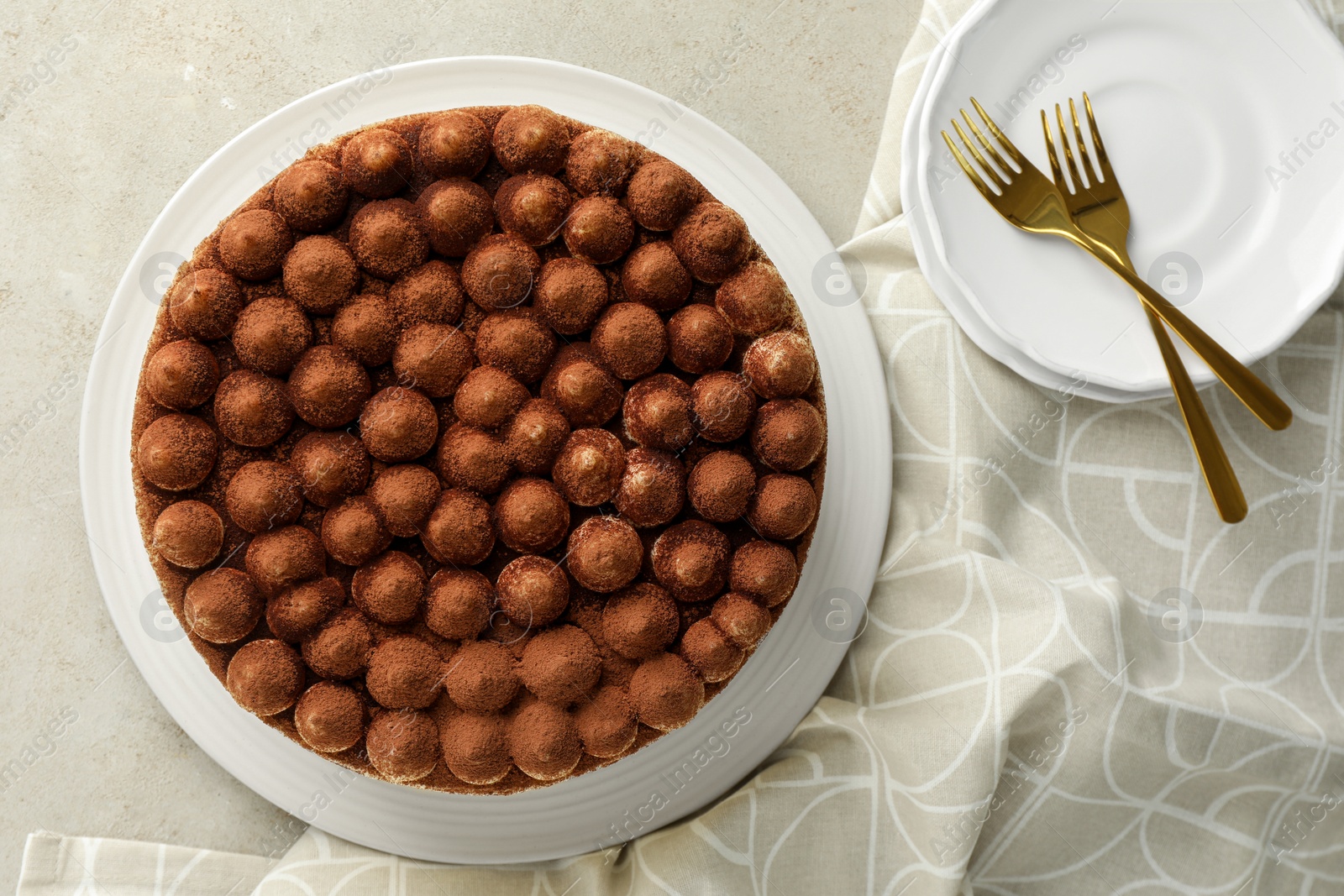 Photo of Delicious tiramisu cake with cocoa powder served on light textured table, flat lay