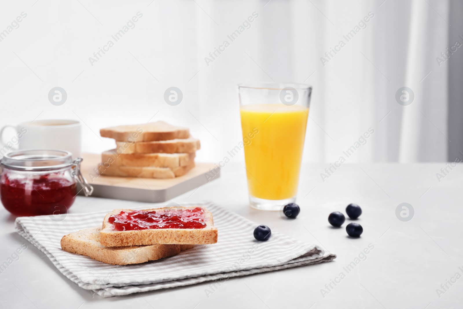 Photo of Toasts with jam and glass of juice on table