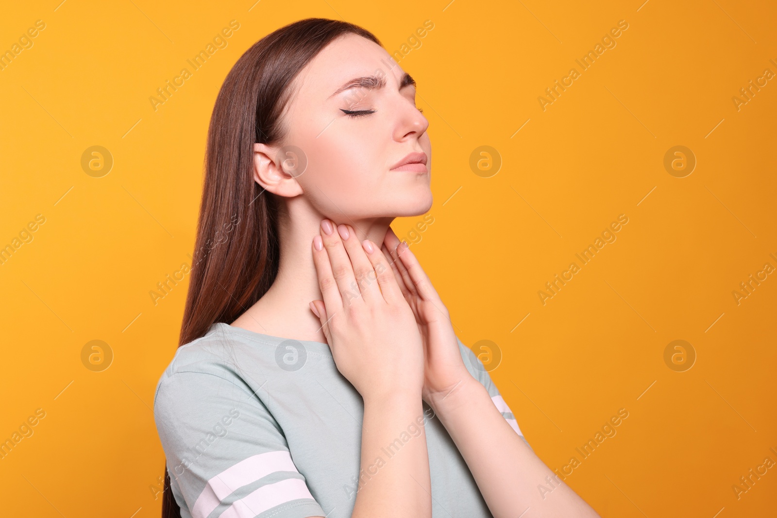 Photo of Young woman with sore throat on orange background