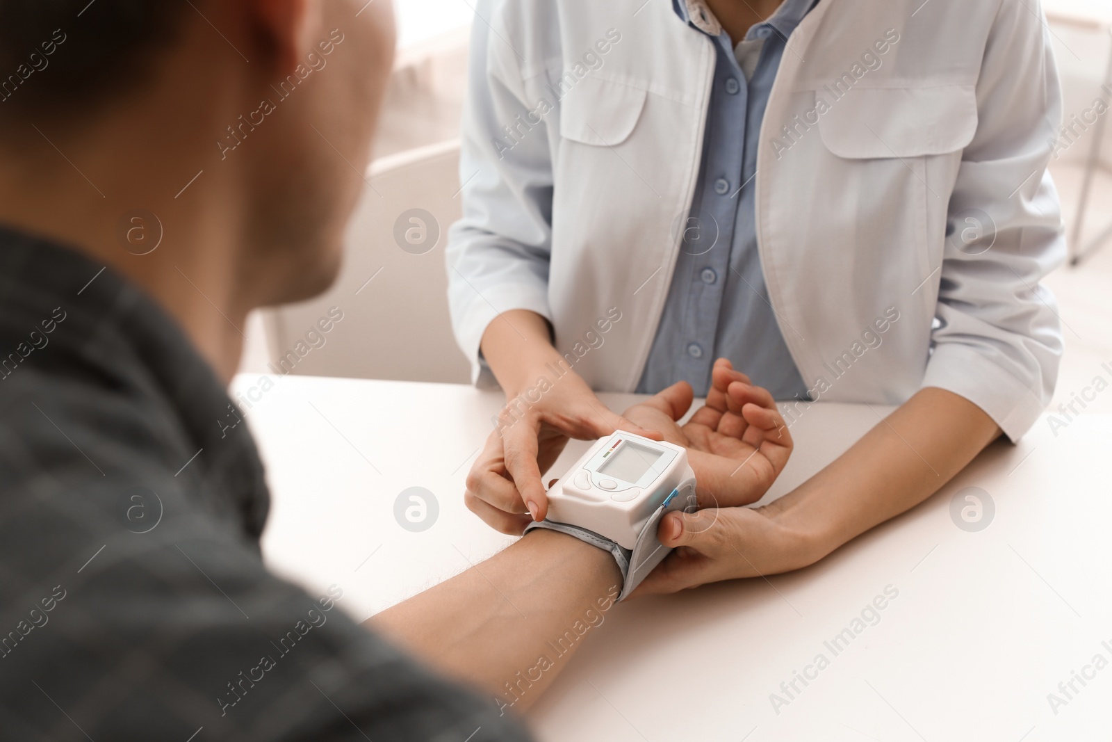 Photo of Doctor checking patient's blood pressure in hospital, closeup. Cardiology concept