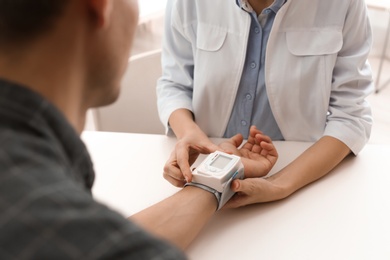 Photo of Doctor checking patient's blood pressure in hospital, closeup. Cardiology concept