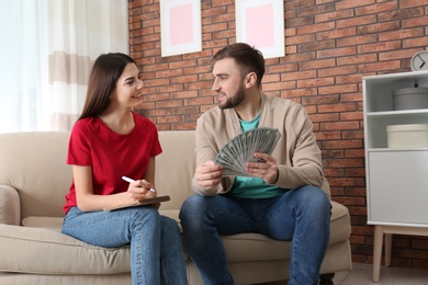 Beautiful young couple with money at home