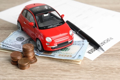 Photo of Toy car, money and insurance contract on table