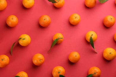 Photo of Fresh ripe tangerines with green leaves on red background, flat lay