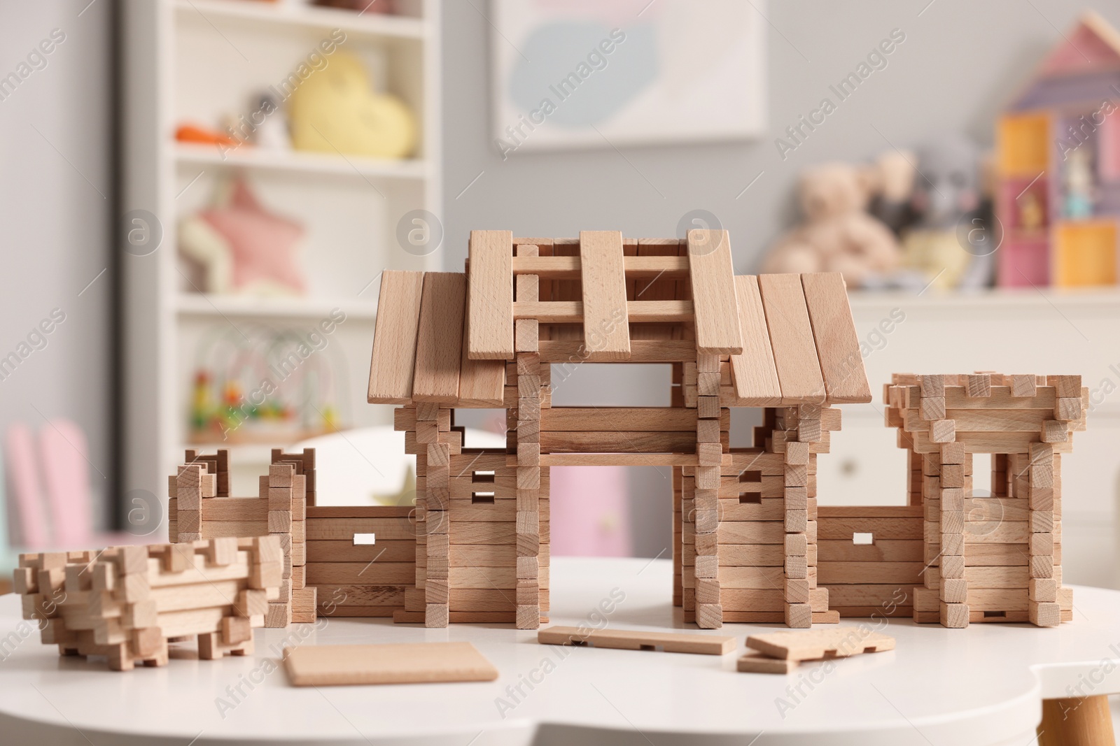 Photo of Wooden entry gate and building blocks on white table indoors. Children's toy