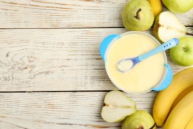 Photo of Baby food in bowl and fresh ingredients on white wooden table, flat lay. Space for text