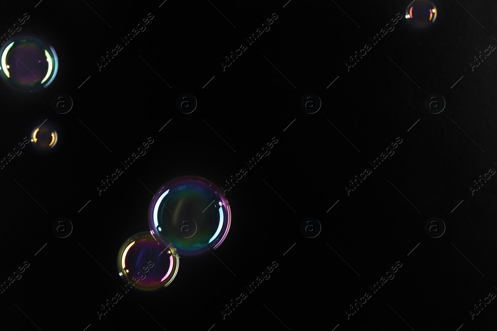 Photo of Beautiful transparent soap bubbles on dark background