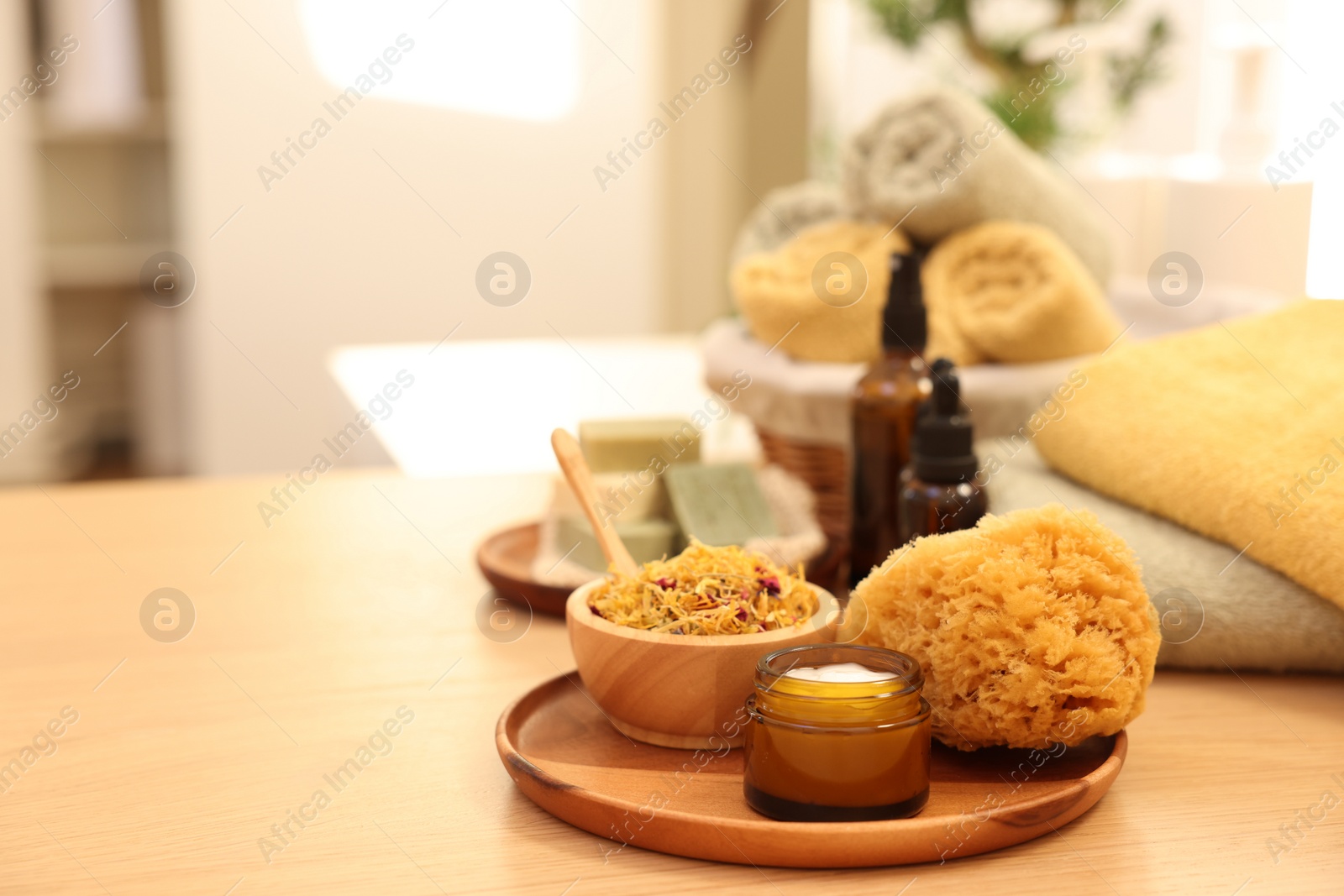 Photo of Dry flowers, loofah and jar with cream on wooden table indoors, space for text. Spa time