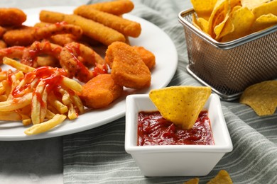Different delicious fast food served with ketchup on light grey table, closeup