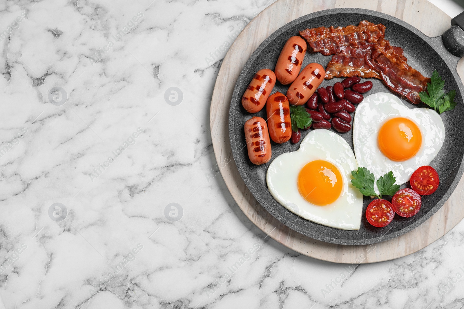 Photo of Delicious breakfast with heart shaped fried eggs and  sausages on white marble table, top view. Space for text