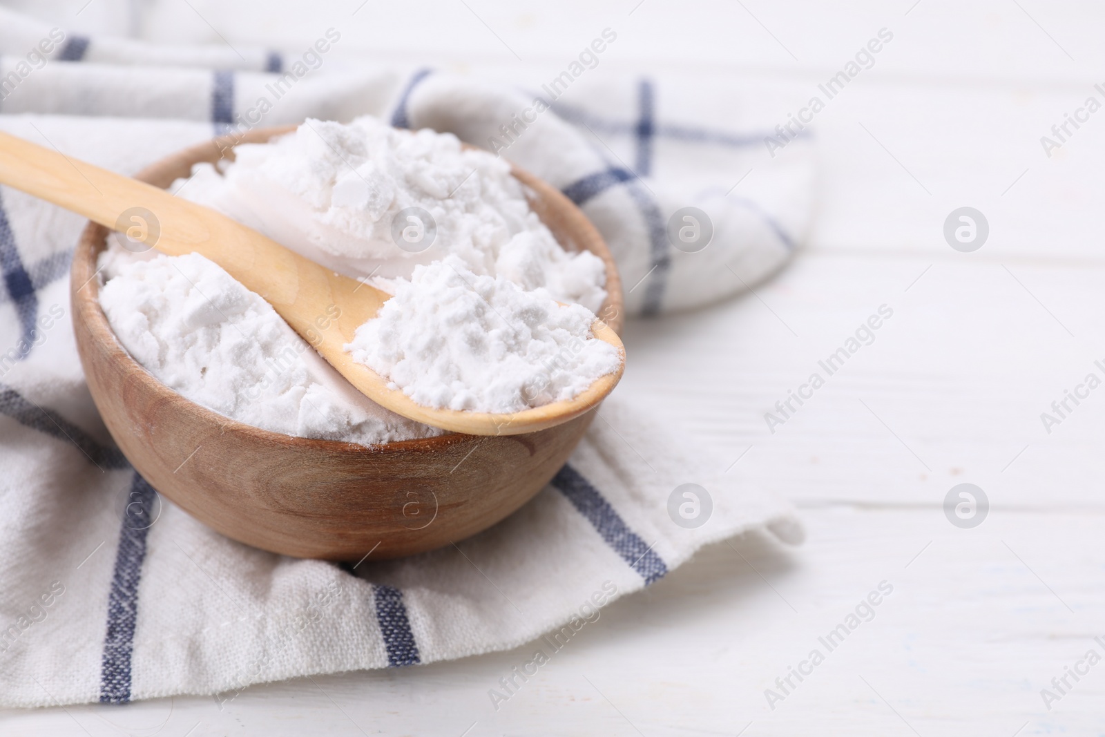 Photo of Bowl and spoon of starch on white wooden table, closeup. Space for text