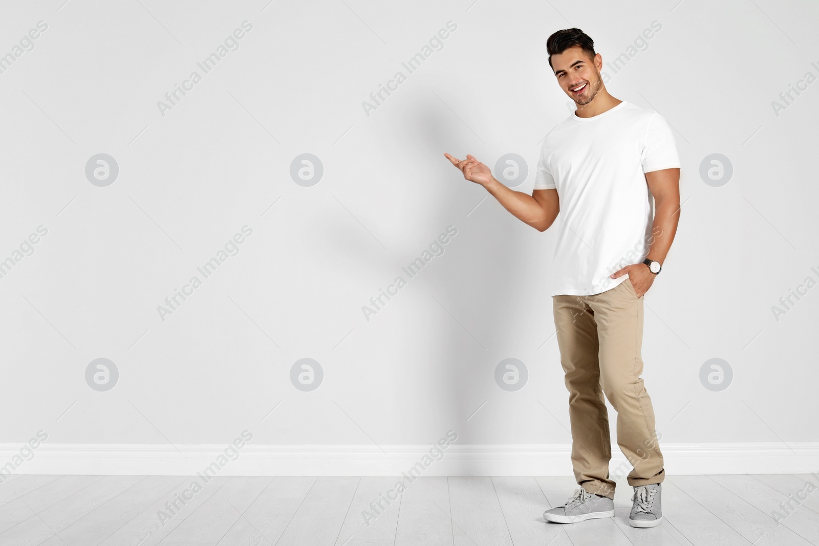 Photo of Full length portrait of handsome young man and space for text on white wall background