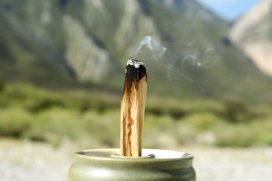 Burning palo santo stick in high mountains, closeup