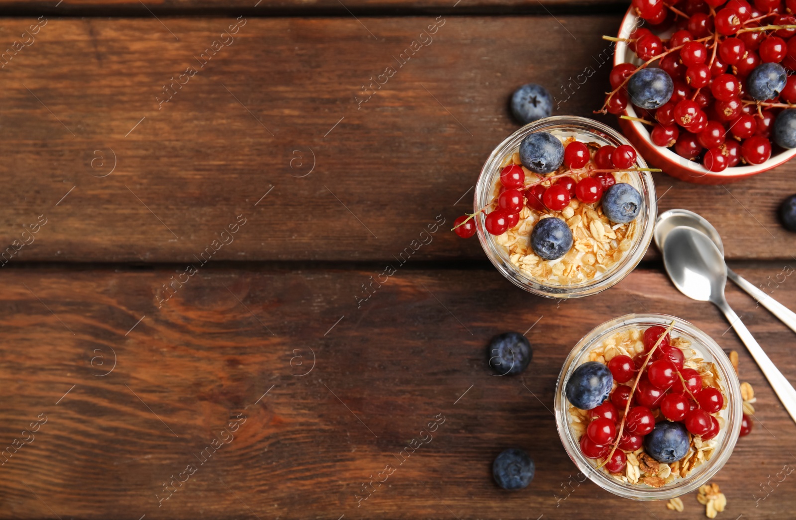 Photo of Delicious yogurt parfait with fresh berries on wooden table, flat lay. Space for text