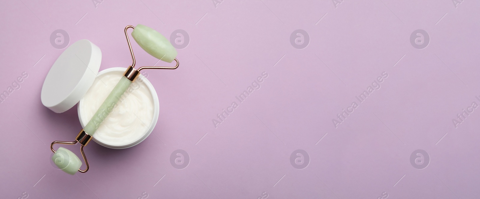 Image of Natural face roller and cosmetic product on lilac background, top view with space for text. Banner design