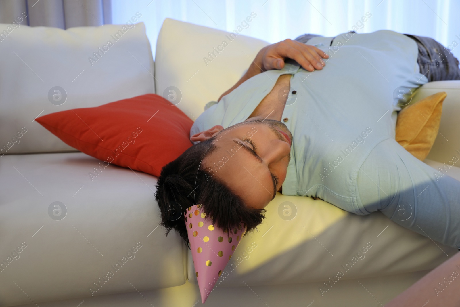 Photo of Young man sleeping on sofa in room after party