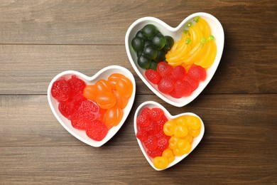 Photo of Delicious gummy fruit shaped candies on wooden table, flat lay