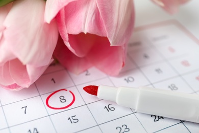 Photo of Tulips and red marker on calendar near date 8th of March, closeup. International Women's Day