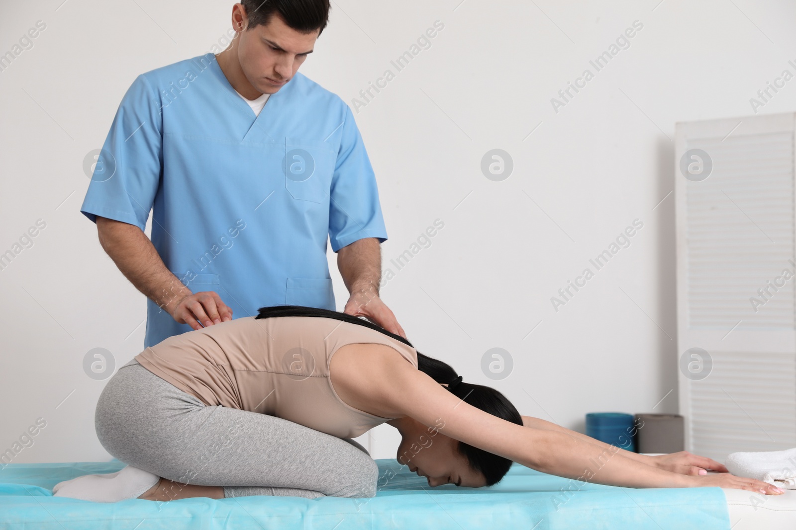 Photo of Orthopedist helping patient to do exercise in clinic, space for text Scoliosis treatment