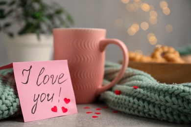 Photo of Note with phrase I Love You near pink cup on table