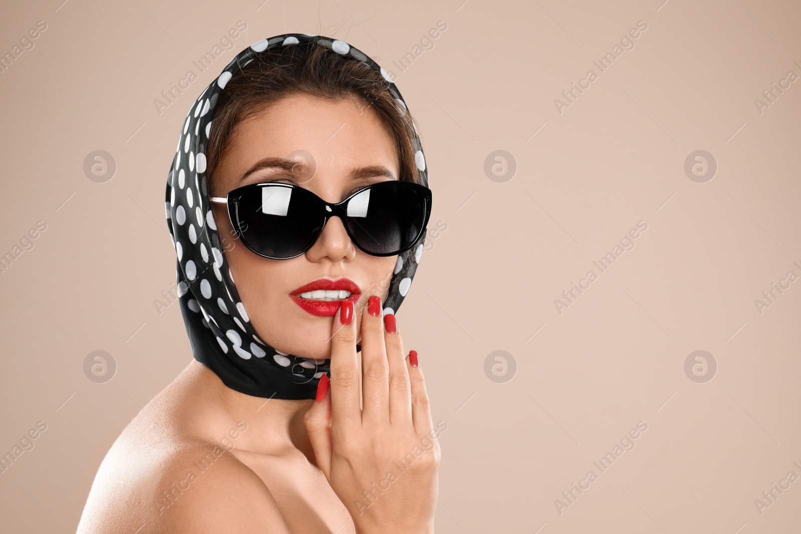 Photo of Young woman wearing stylish sunglasses and headscarf on beige background. Space for text