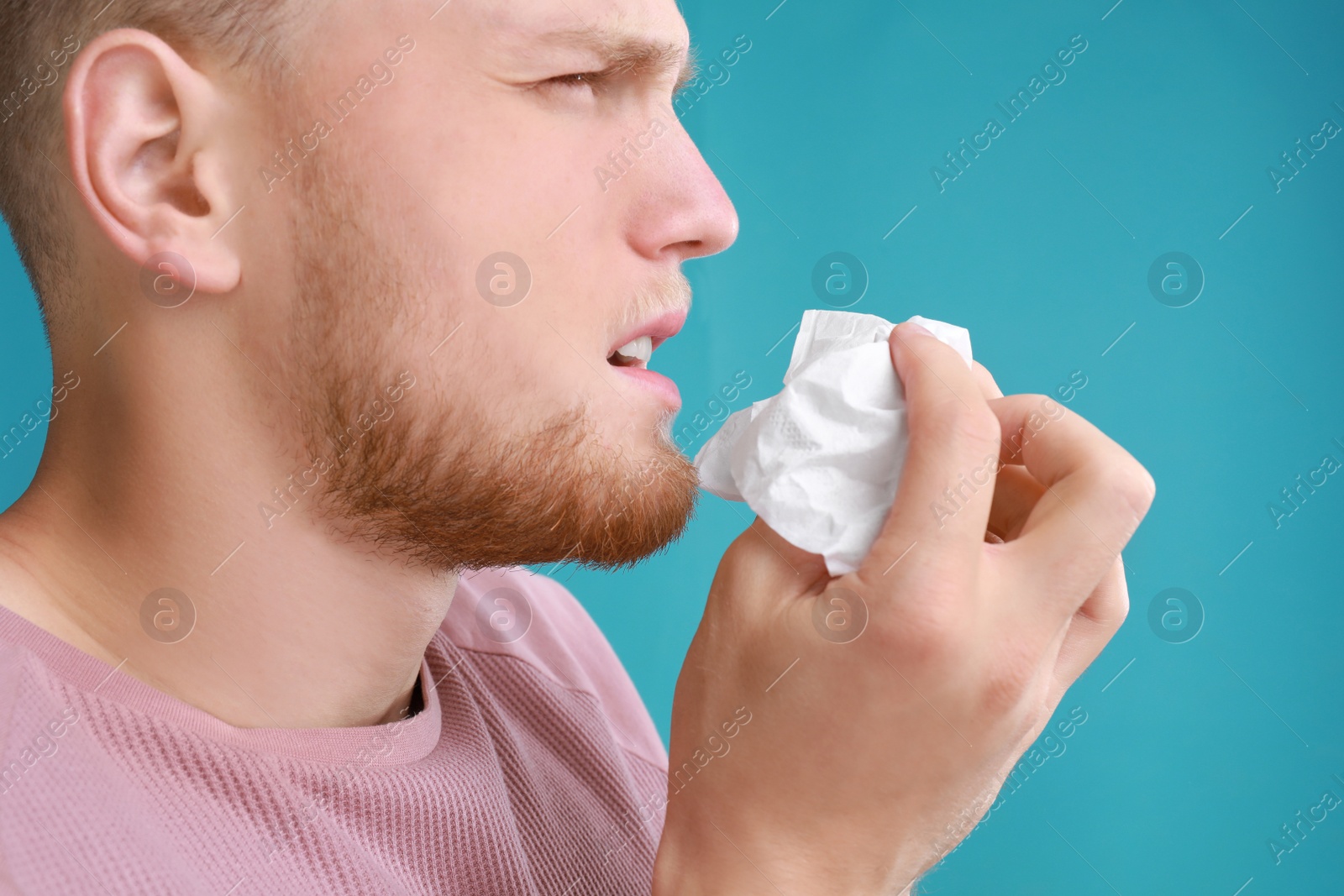 Photo of Young man suffering from allergy on blue background