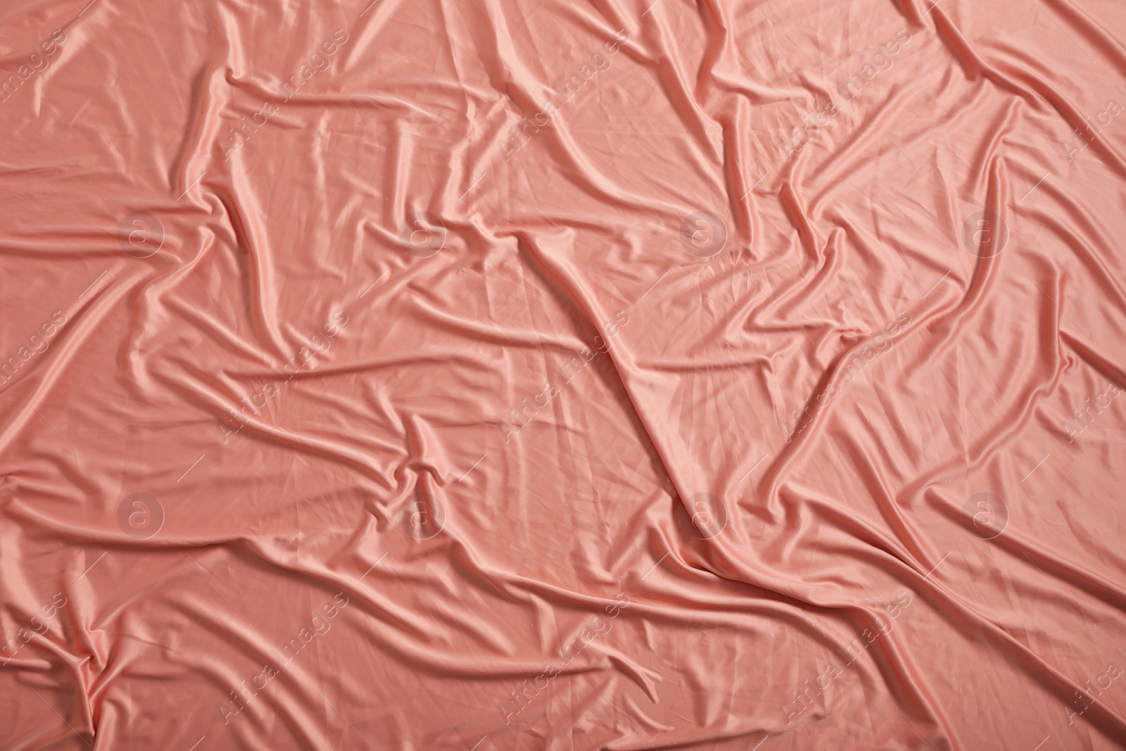 Photo of Crumpled coral fabric as background, closeup view