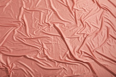 Photo of Crumpled coral fabric as background, closeup view