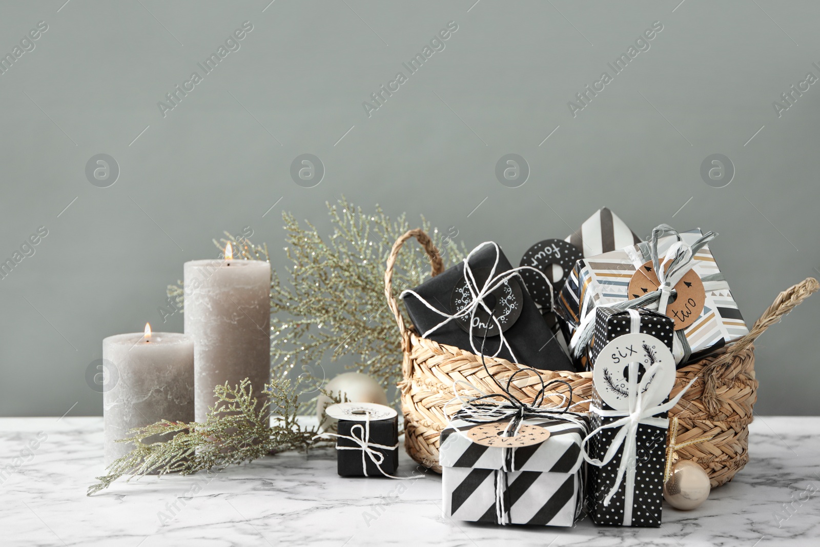 Photo of Gifts for Christmas advent calendar, burning candles and festive decor on white marble table against grey background