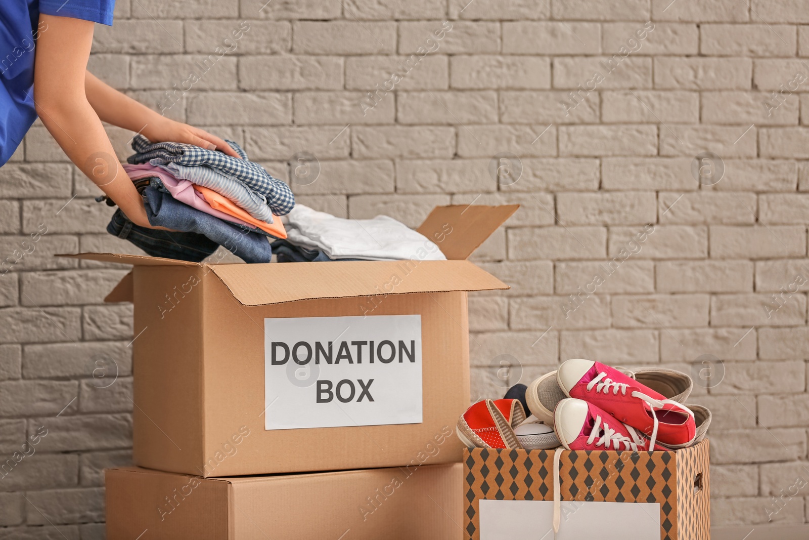 Photo of Volunteer collecting clothes into donation boxes indoors