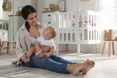 Photo of Happy young mother with her baby in nursery. Space for text