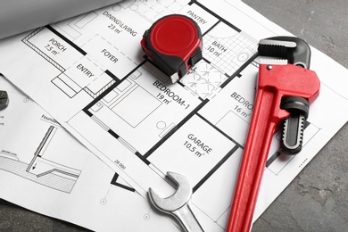 Photo of House plan with plumber's tools on grey table