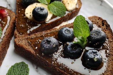 Photo of Tasty toast with blueberries, honey and chia seeds on plate, closeup