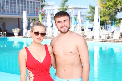 Happy young couple near swimming pool at resort