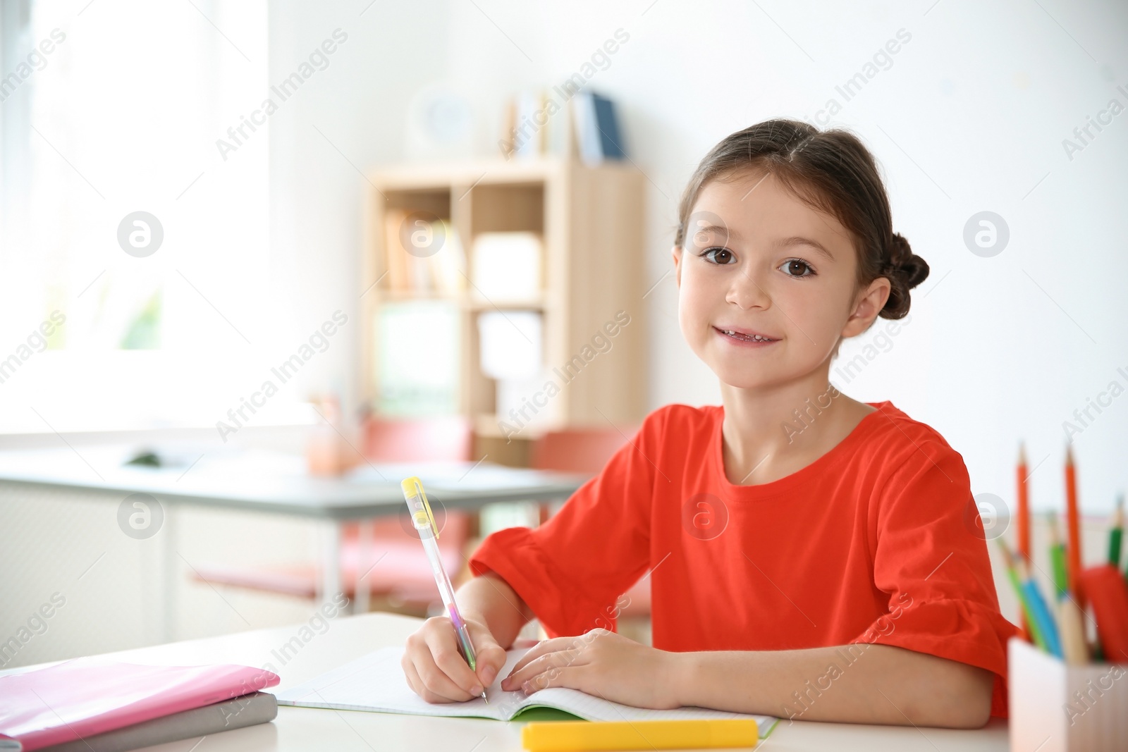 Photo of Cute little child doing assignment at desk in classroom. Elementary school