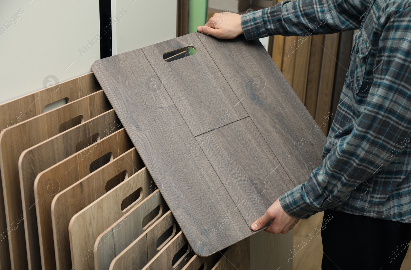 Photo of Man with sample of wooden flooring in shop, closeup