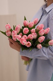 Woman with bouquet of beautiful fresh tulips on light grey background, closeup