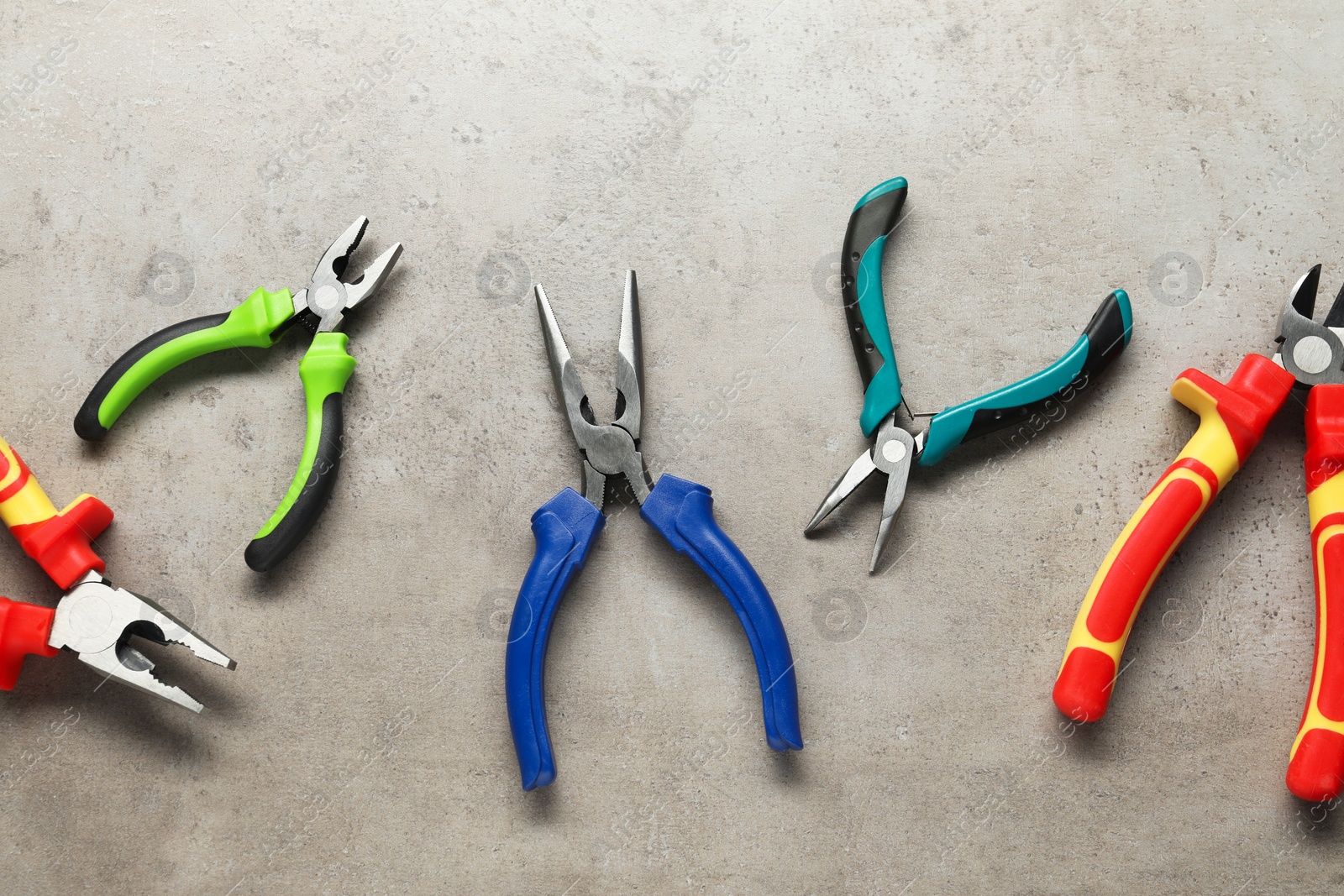 Photo of Different pliers on grey textured table, flat lay