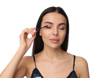 Young woman applying mascara on white background