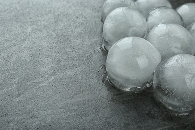 Photo of Many melting ice balls on dark grey table, closeup. Space for text