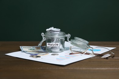 Glass jar with word Pension, money and glasses on wooden table