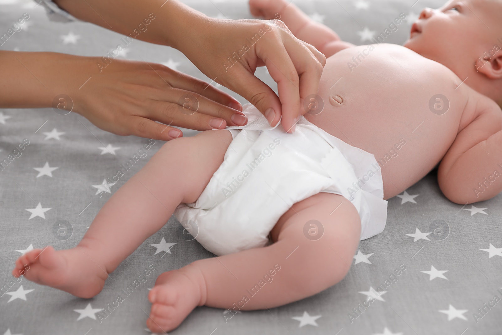 Photo of Mother changing her baby's diaper on bed