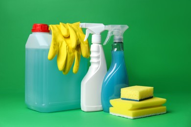 Photo of Different cleaning supplies and tools on green background