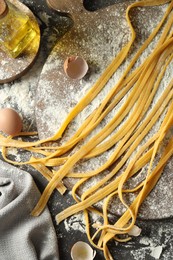 Photo of Homemade pasta, flour, eggs and oil on dark grey table, flat lay