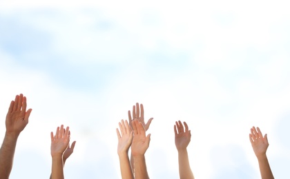 Photo of Group of volunteers raising hands outdoors, closeup