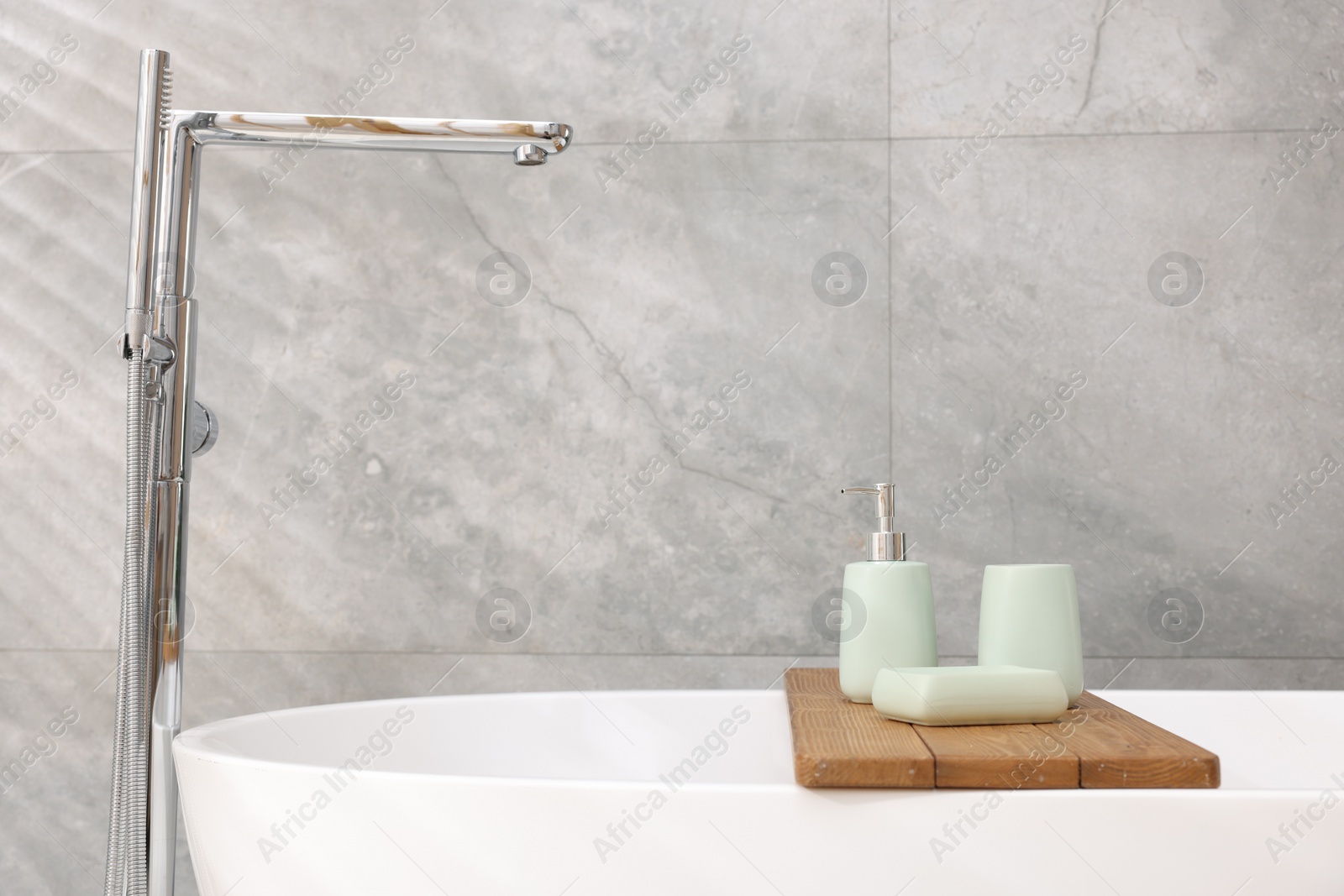 Photo of Set of bath accessories on tub in bathroom, space for text