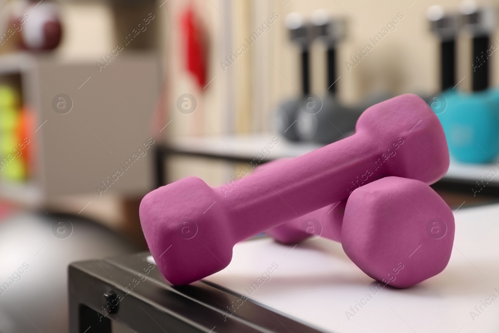 Photo of Pink dumbbells on white table indoors, closeup. Sports equipment