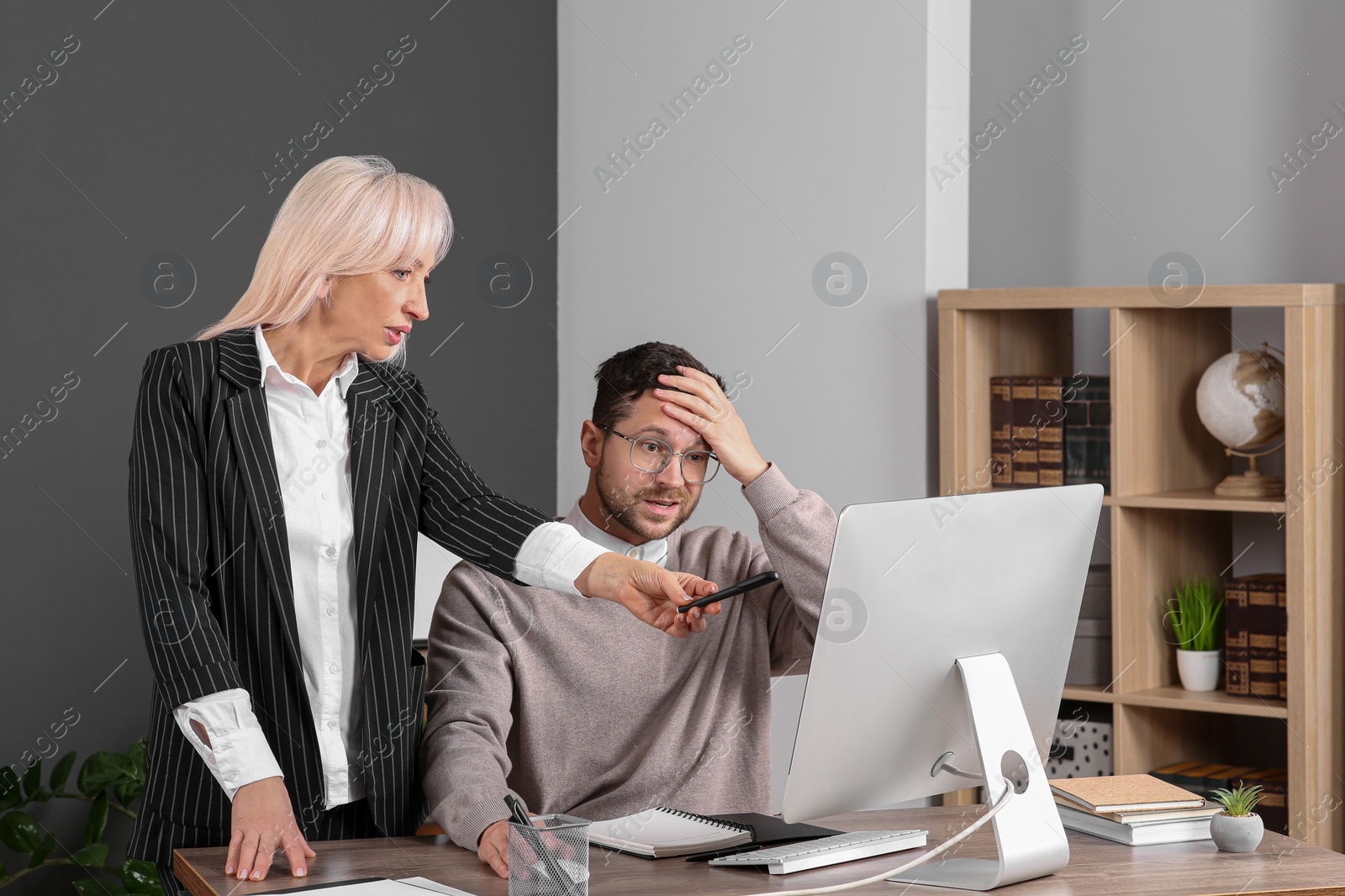 Photo of Confused employee and boss pointing at computer in office