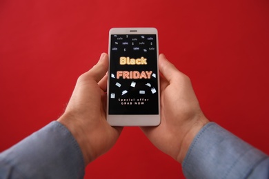 Photo of Man shopping online using smartphone on red background, closeup. Black Friday Sale